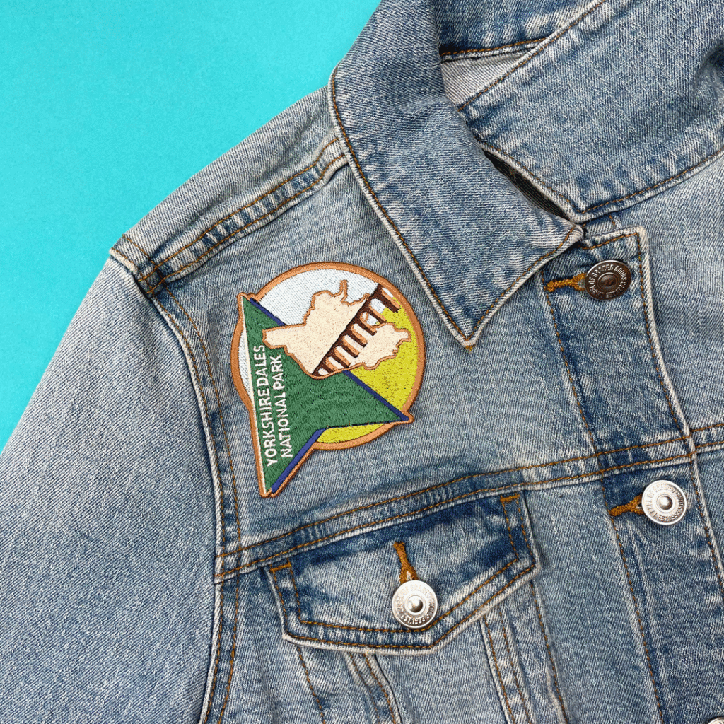 Denim jacket with colorful Yorkshire Dales National Park patch, map, and stripes on blue.