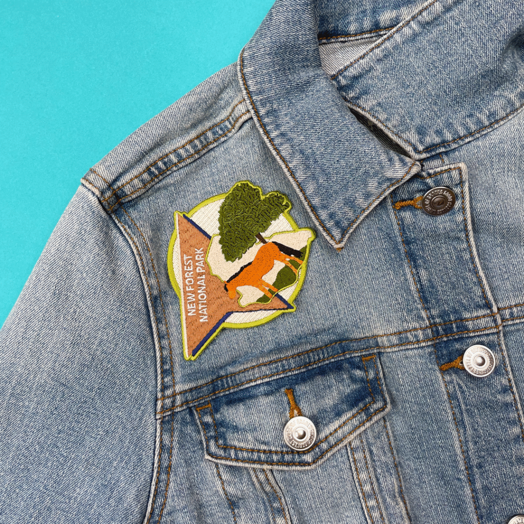Denim jacket with colorful New Forest National Park patch—tree, deer, star border, blue background.