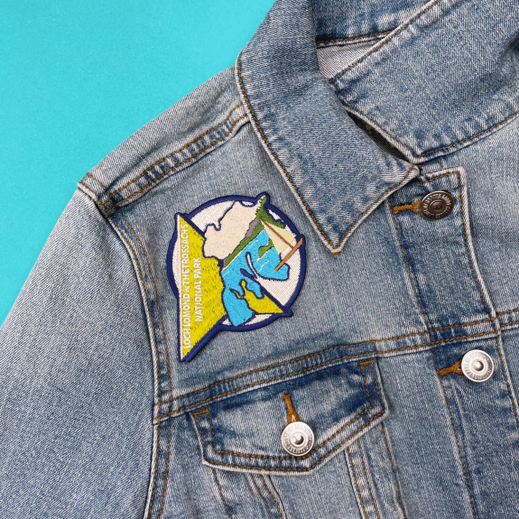Blue denim jacket with a mountain patch, water, trees, and Voyage Mountain Adventure Park.