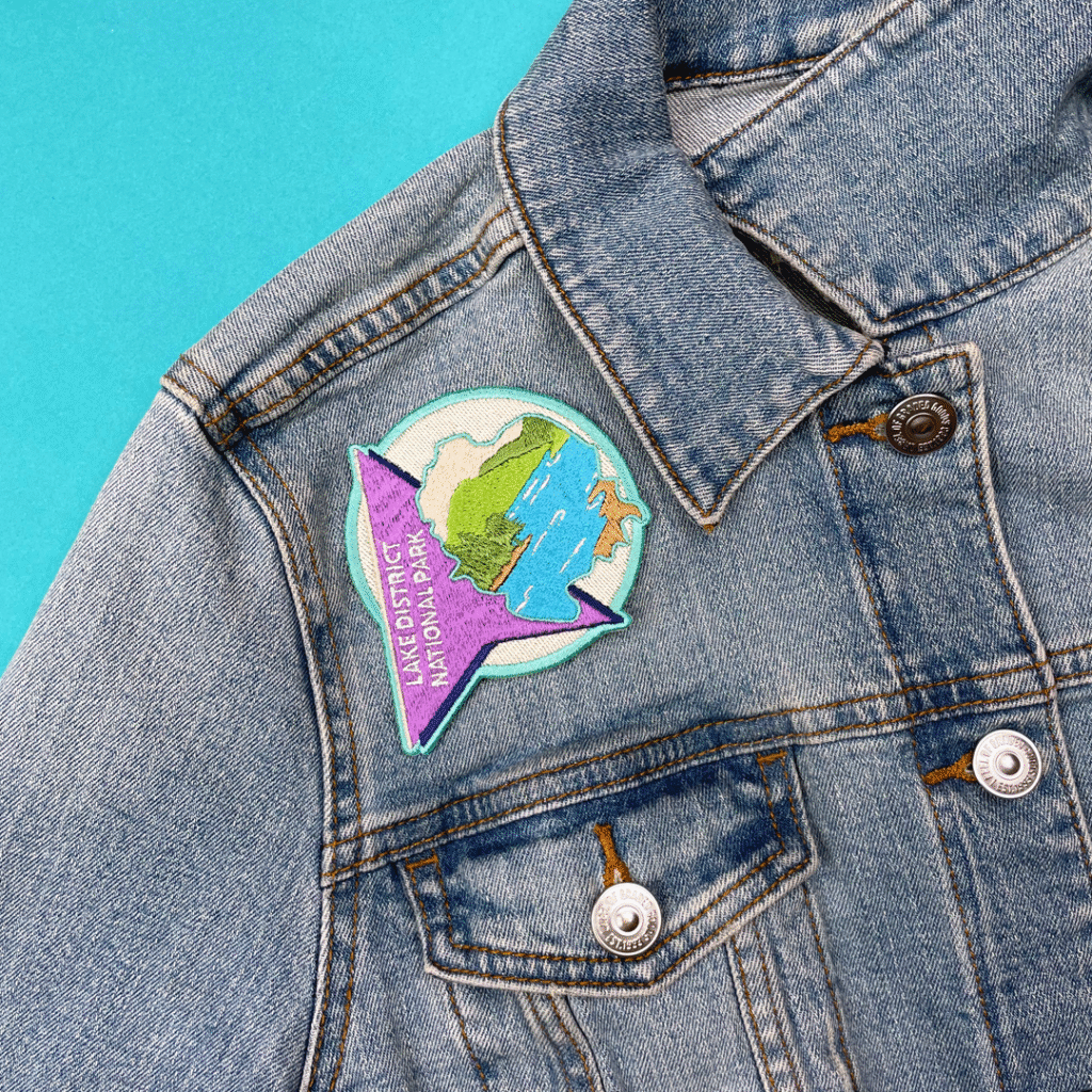 Denim jacket with an Earth patch on the shoulder and a purple Cyrillic speech bubble, light blue bg.