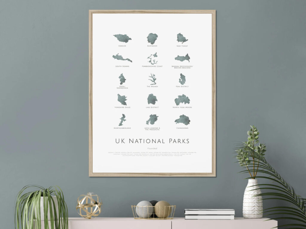 Silhouetted UK National Parks poster emphasizing partnerships, above a shelf with plants and decor.